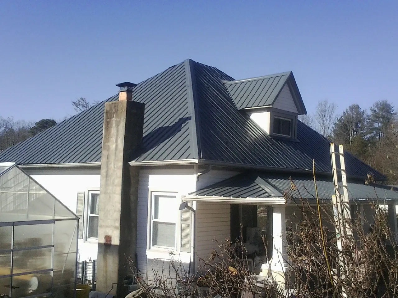 Dark blue standing seam metal roof on a white farmhouse with dormer — Slate & Tile Roof Repair by Roofing Brothers in Knightstown