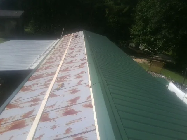 Old rusted panels beside newly installed green metal roofing — Wind Damage Roof Repair by Roofing Brothers in Knightstown