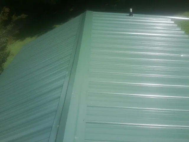 New green metal panels meeting at the ridge of a roof — Flat Roof Repair work by our crew in Knightstown