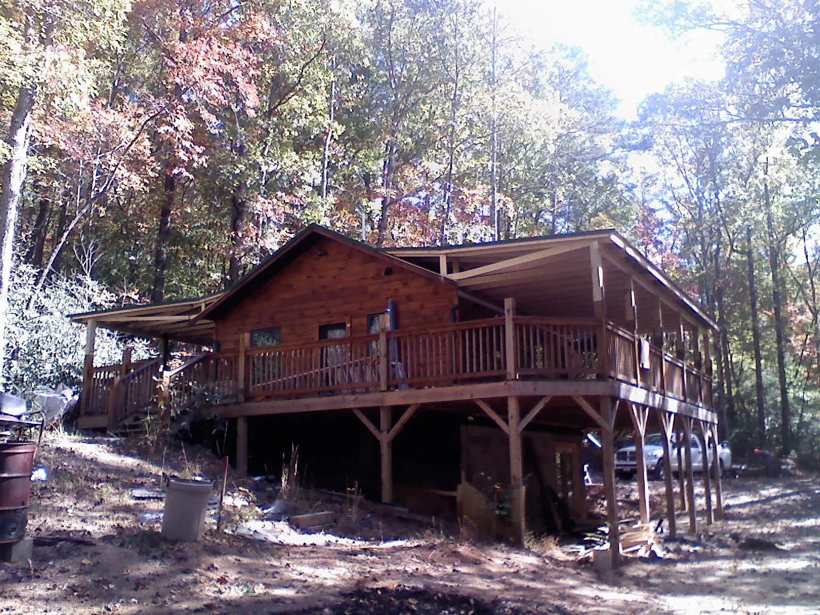 Log cabin with a wraparound porch and metal roof in the fall in Knightstown