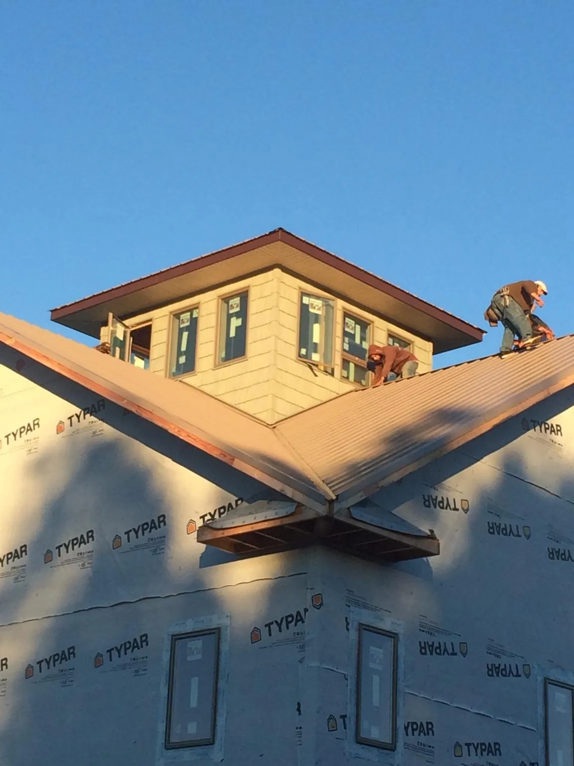 Roofers working around a rooftop cupola on a new metal roof at sunset — Roof Waterproofing in Knightstown by Roofing Brothers